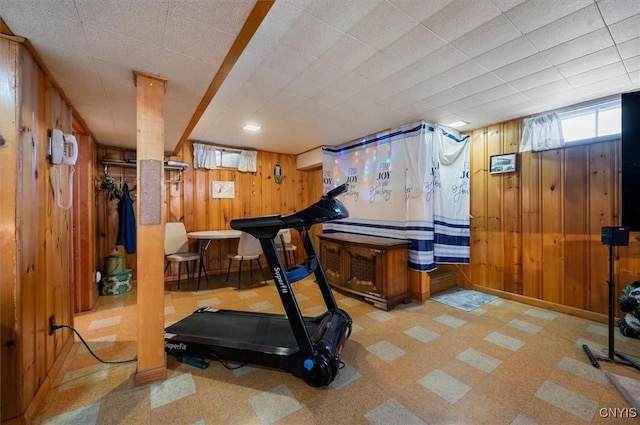 workout area with baseboards, wood walls, and tile patterned floors