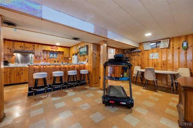 workout room featuring bar area, visible vents, wooden walls, and light floors