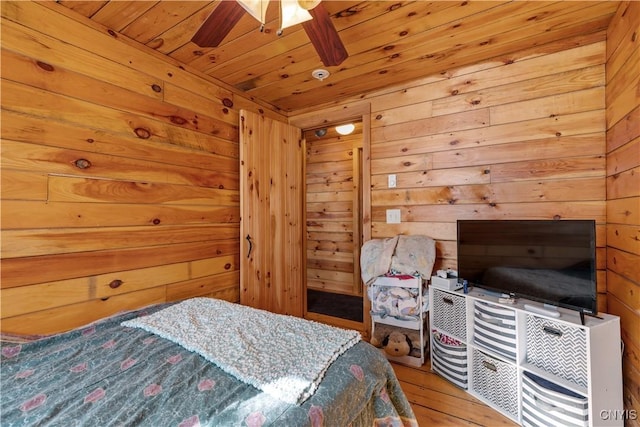 bedroom with wooden ceiling, wooden walls, and wood finished floors