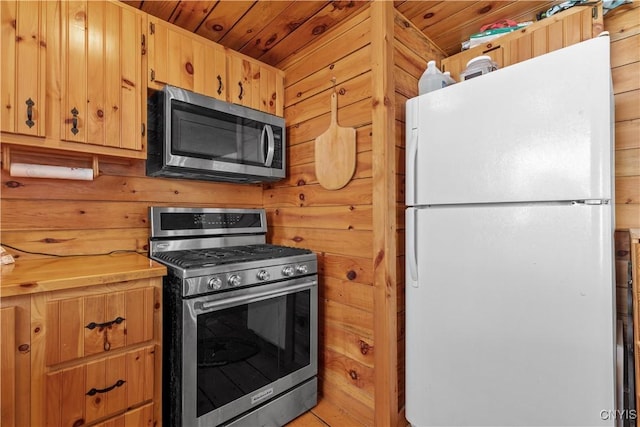 kitchen with appliances with stainless steel finishes, wood walls, and wood ceiling