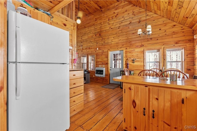 kitchen featuring heating unit, freestanding refrigerator, wood walls, light wood-type flooring, and wooden ceiling