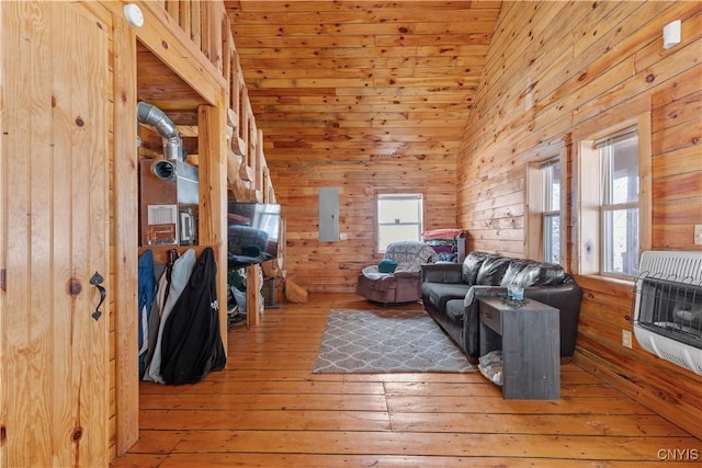 living room featuring high vaulted ceiling, hardwood / wood-style floors, wooden walls, and heating unit