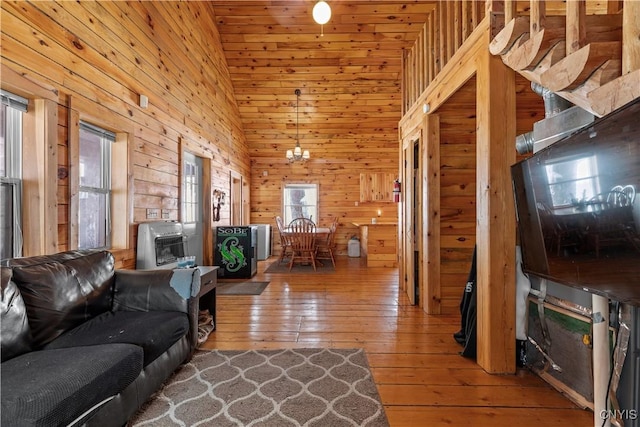 living room featuring heating unit, wooden walls, high vaulted ceiling, and hardwood / wood-style floors