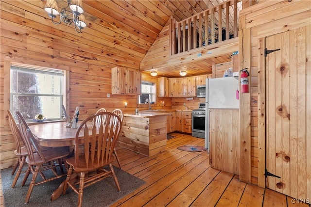 dining area featuring vaulted ceiling, light wood-style floors, wooden ceiling, and wood walls