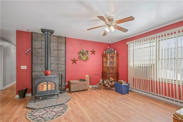 284 Main St, Worcester, NY 12197 - interior space with a baseboard heating unit, a ceiling fan, a wood stove, wood finished floors, and baseboards