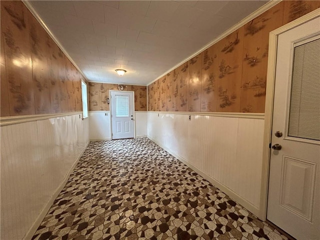 hall with a wainscoted wall and ornamental molding