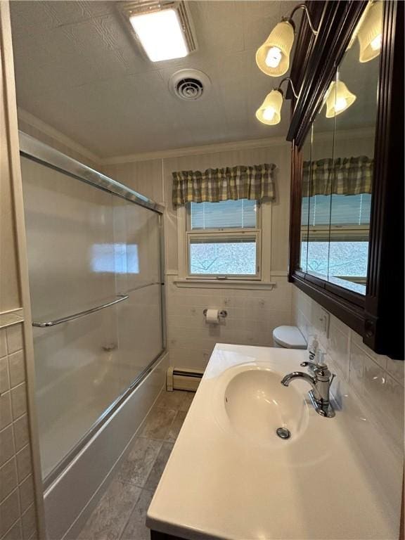 full bathroom with visible vents, combined bath / shower with glass door, tile walls, a baseboard radiator, and vanity