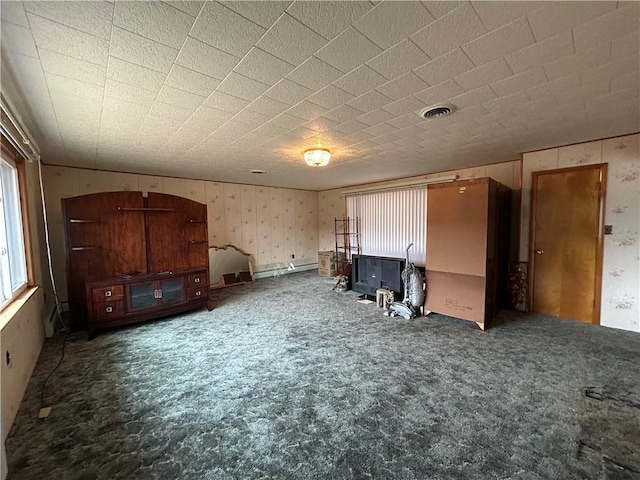 interior space featuring visible vents, wallpapered walls, a baseboard heating unit, carpet, and a wood stove