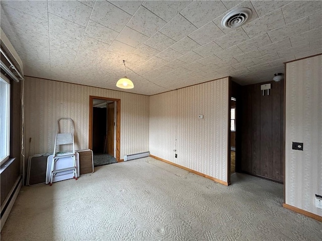 empty room with visible vents, wallpapered walls, a baseboard heating unit, baseboards, and a baseboard radiator