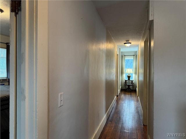 hallway featuring dark wood finished floors and baseboards