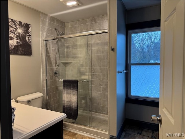 full bath featuring toilet, a shower stall, vanity, and baseboards