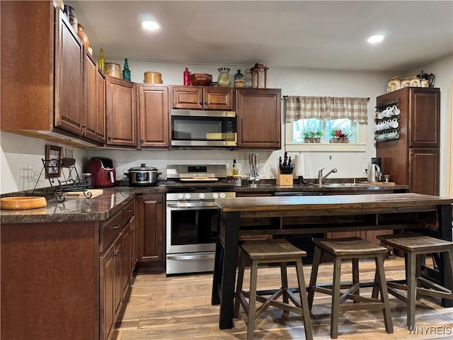 kitchen with stainless steel appliances, light wood finished floors, a sink, and recessed lighting