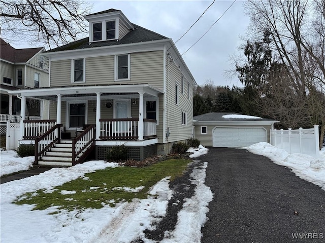 american foursquare style home featuring an outbuilding, covered porch, fence, and a detached garage