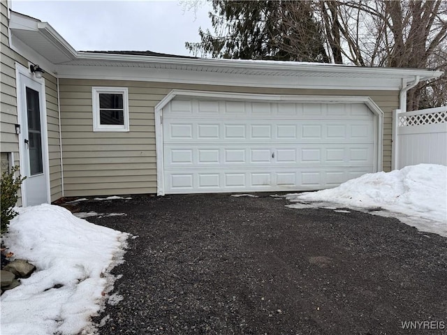 garage with aphalt driveway and fence