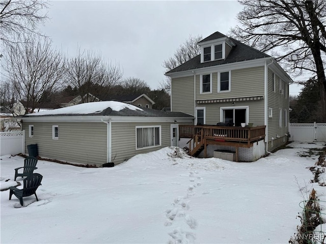 snow covered house with fence and a deck