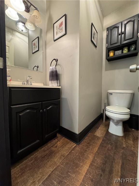 bathroom with wood finished floors, vanity, toilet, and baseboards