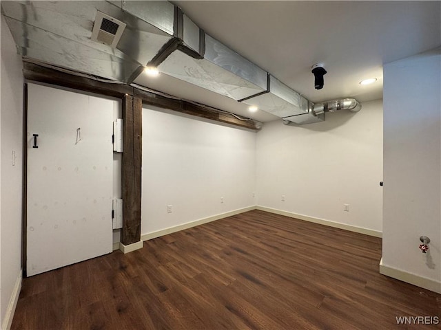 finished below grade area featuring baseboards, visible vents, and wood finished floors