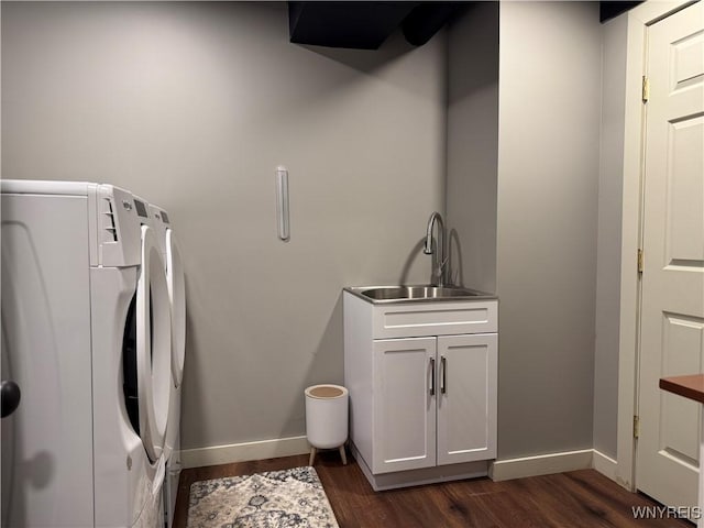 clothes washing area with cabinet space, baseboards, dark wood-type flooring, washing machine and clothes dryer, and a sink