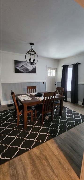 dining space with wainscoting, wood finished floors, and an inviting chandelier