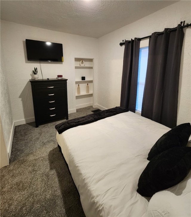 bedroom featuring a textured ceiling, dark colored carpet, and a textured wall