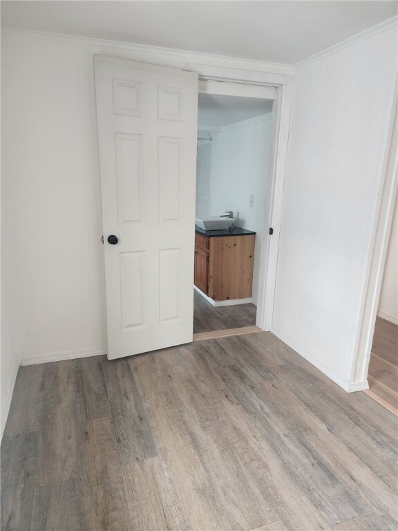 empty room with baseboards, wood finished floors, and crown molding