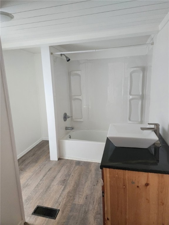 bathroom with shower / bathtub combination, wood finished floors, vanity, visible vents, and baseboards