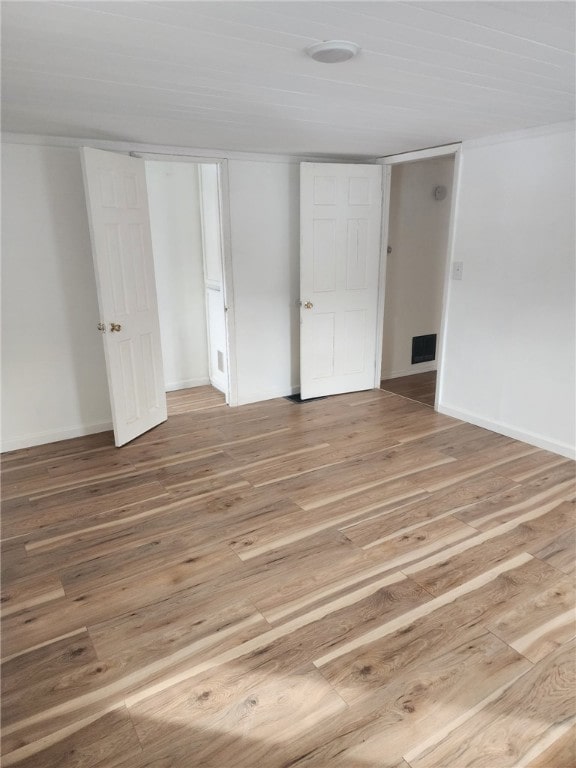 unfurnished bedroom with light wood-type flooring, a closet, visible vents, and baseboards