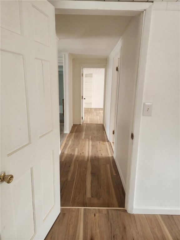 hallway featuring baseboards and wood finished floors