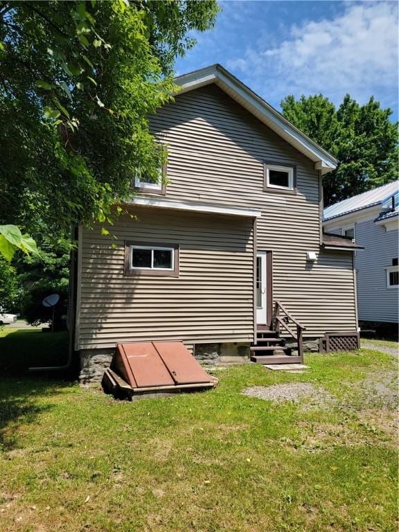 back of property featuring entry steps and a yard