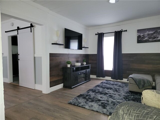 living area with a barn door, wood finished floors, and a wainscoted wall