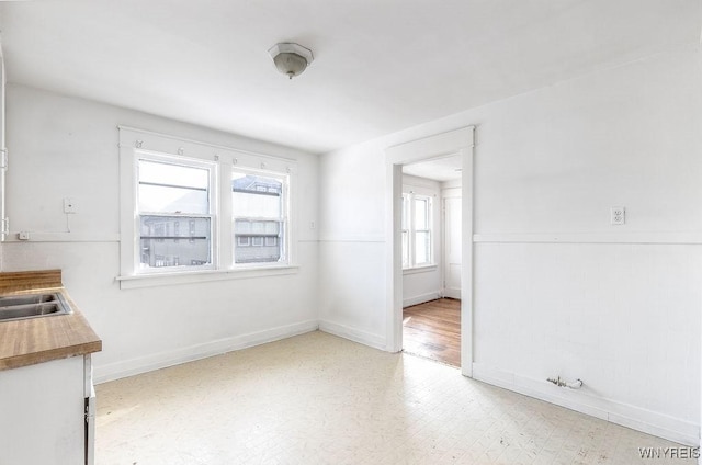 unfurnished dining area featuring light floors and baseboards