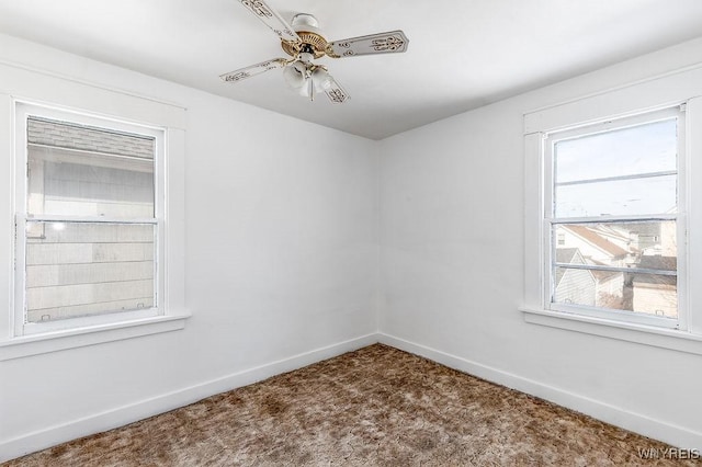 carpeted spare room with a ceiling fan and baseboards