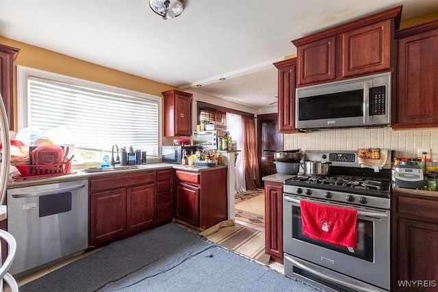 kitchen with appliances with stainless steel finishes, a sink, dark brown cabinets, and tasteful backsplash