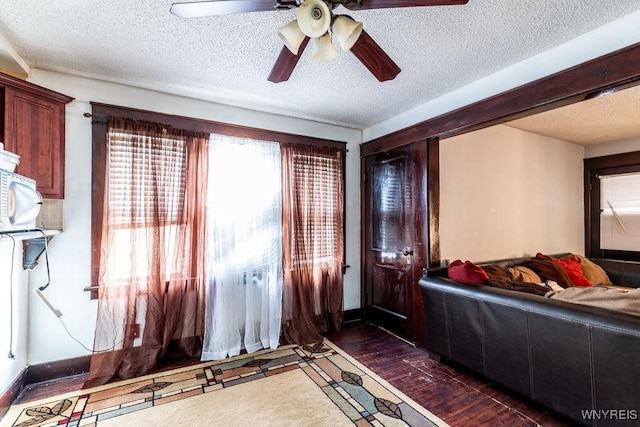 bedroom with a textured ceiling, dark wood-style flooring, a ceiling fan, and baseboards