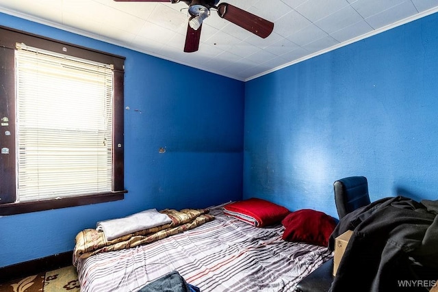 bedroom with ceiling fan, multiple windows, ornamental molding, and a textured wall