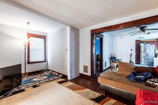 living area with visible vents, ceiling fan, a textured ceiling, and wood finished floors