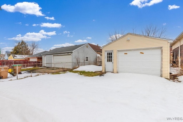 exterior space with a detached garage, fence, and an outbuilding