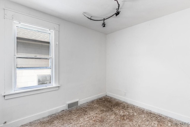 unfurnished room featuring rail lighting, baseboards, and visible vents