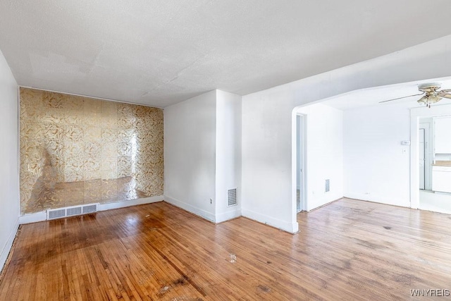 empty room with wood finished floors, visible vents, and a ceiling fan