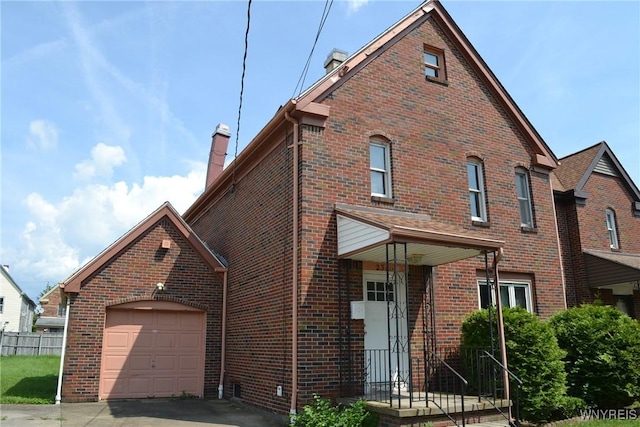 view of front of property with brick siding, fence, a chimney, and an attached garage