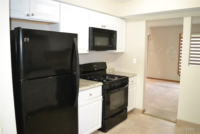 kitchen featuring baseboards, white cabinets, light colored carpet, light stone countertops, and black appliances