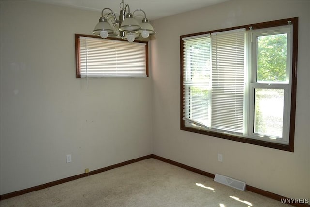 empty room featuring baseboards, an inviting chandelier, visible vents, and light colored carpet