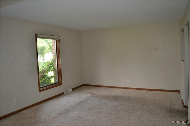 spare room with visible vents, light carpet, and baseboards