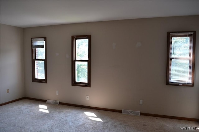 spare room featuring baseboards, visible vents, and light colored carpet