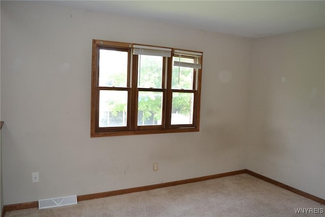 empty room featuring light carpet, baseboards, and visible vents