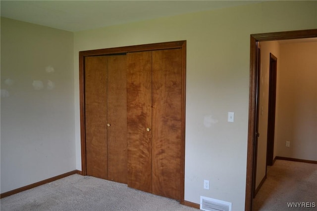 unfurnished bedroom featuring a closet, carpet flooring, visible vents, and baseboards