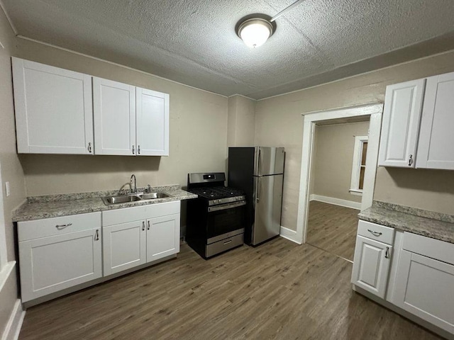 kitchen with white cabinets, dark wood-style floors, appliances with stainless steel finishes, light countertops, and a sink