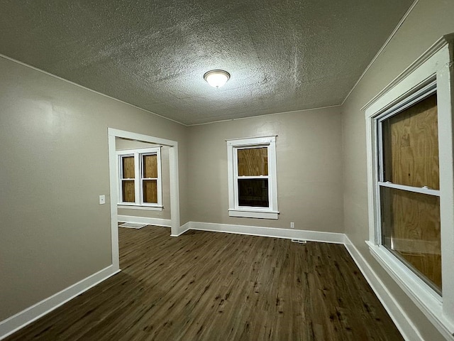 unfurnished room featuring visible vents, a textured ceiling, baseboards, and dark wood-style flooring