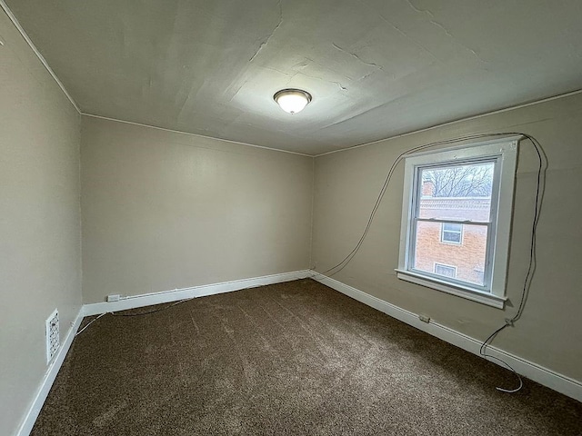 unfurnished room featuring dark colored carpet, visible vents, and baseboards