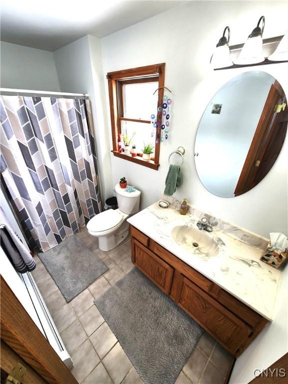 bathroom with tile patterned flooring, vanity, toilet, and a shower with curtain